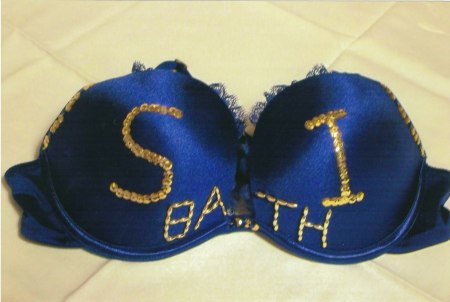 A blue bra, decorated with gold lettering, reading, S.I. Bath